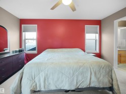 Bedroom with light colored carpet, ceiling fan, multiple windows, and connected bathroom - 