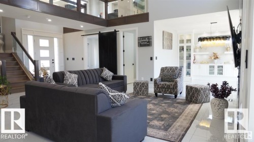 Tiled living room featuring a barn door, stairs, a towering ceiling, and recessed lighting - 707 180 Street, Edmonton, AB - Indoor Photo Showing Other Room