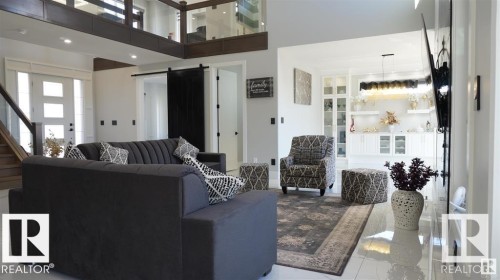 Living area featuring a barn door, a towering ceiling, stairs, and tile patterned floors - 707 180 Street, Edmonton, AB - Indoor