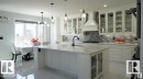 Kitchen featuring glass insert cabinets, white cabinets, hanging light fixtures, custom exhaust hood, and light stone counters - 707 180 Street, Edmonton, AB  - Indoor Photo Showing Kitchen With Upgraded Kitchen 