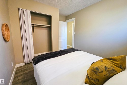 Bedroom featuring a textured ceiling, dark wood finished floors, and a closet - 4203 83 Street, Edmonton, AB - Indoor Photo Showing Bedroom