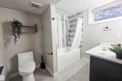Full bathroom with shower / bath combo, vanity, a textured ceiling, and light tile patterned floors - 4203 83 Street, Edmonton, AB - Indoor Photo Showing Bathroom