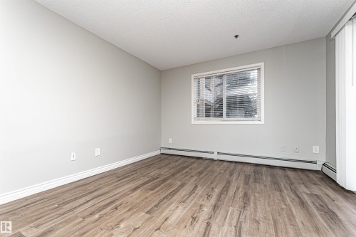 Spare room featuring light wood finished floors, a textured ceiling, and a baseboard radiator - 108 2305 35A Avenue, Edmonton, AB - Indoor Photo Showing Other Room