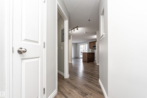 Hallway with a textured ceiling, dark wood-style floors, and a baseboard heating unit - 108 2305 35A Avenue, Edmonton, AB - Indoor Photo Showing Other Room
