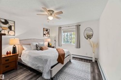 Bedroom with baseboard heating, dark wood-type flooring, a ceiling fan, and a textured ceiling - 
