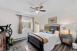 Bedroom featuring a ceiling fan, a baseboard heating unit, dark wood-style floors, and a textured ceiling - 