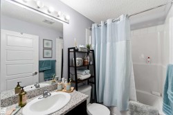 Bathroom with a textured ceiling, shower / bath combo with shower curtain, and vanity - 