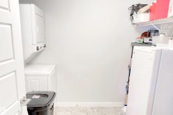 Washroom featuring stacked washer and clothes dryer and light tile patterned flooring - 