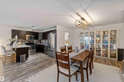 Dining space featuring light wood-style flooring, a chandelier, and a textured ceiling - 