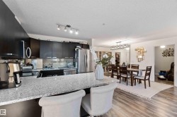 Kitchen featuring dark cabinets, a breakfast bar, tasteful backsplash, light stone counters, and a textured ceiling - 