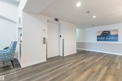 Empty room with elevator, wood finished floors, and recessed lighting - 209 10915 21 Avenue, Edmonton, AB 