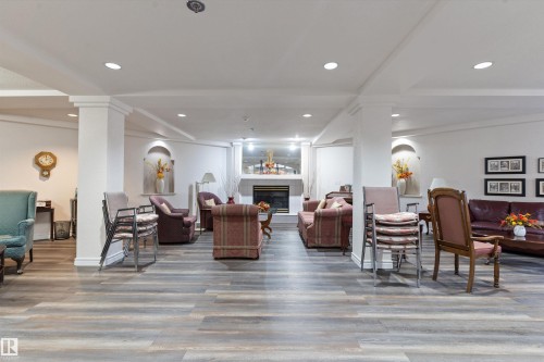 Living room featuring a tile fireplace, decorative columns, light wood-style flooring, and recessed lighting - 209 10915 21 Avenue, Edmonton, AB 