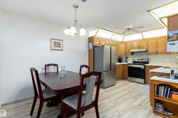 Kitchen featuring light countertops, stainless steel appliances, decorative light fixtures, decorative backsplash, and light wood-style flooring - 