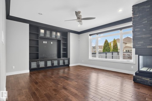 Unfurnished living room with ornamental molding, ceiling fan, dark wood-type flooring, built in features, and recessed lighting - 8536 19 Avenue, Edmonton, AB - Indoor