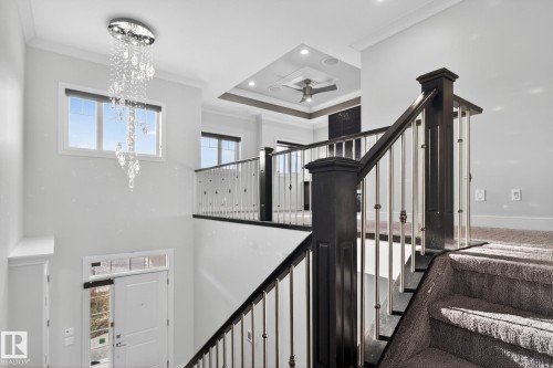 Stairway with crown molding, a tray ceiling, recessed lighting, ceiling fan, and a chandelier - 8536 19 Avenue, Edmonton, AB - Indoor Photo Showing Other Room