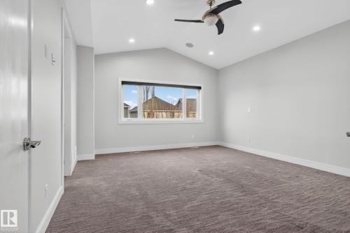 Carpeted spare room featuring vaulted ceiling, a ceiling fan, and recessed lighting - 8536 19 Avenue, Edmonton, AB - Indoor