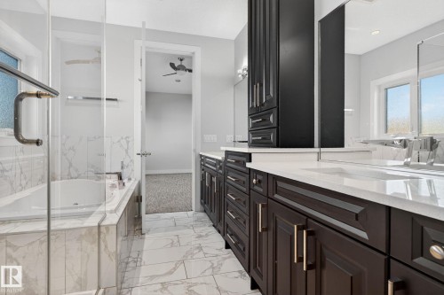 Full bath featuring healthy amount of natural light, vanity, a tub with marble appearance, and light marble finish flooring - 8536 19 Avenue, Edmonton, AB - Indoor Photo Showing Bathroom