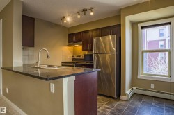 Kitchen with appliances with stainless steel finishes, dark stone counters, dark brown cabinets, under cabinet range hood, and a peninsula - 
