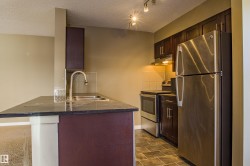 Kitchen with appliances with stainless steel finishes, dark brown cabinets, a textured ceiling, under cabinet range hood, and decorative backsplash - 