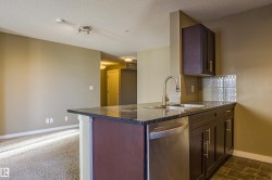 Kitchen featuring dishwasher, dark stone counters, decorative backsplash, a peninsula, and a textured ceiling - 