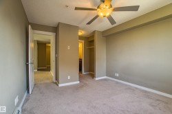 Unfurnished bedroom with a textured ceiling, light carpet, ceiling fan, a closet, and a baseboard heating unit - 