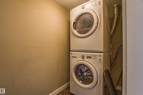 Laundry area featuring stacked washer / drying machine and a textured ceiling - 201 5804 Mullen Place, Edmonton, AB - Indoor Photo Showing Laundry Room