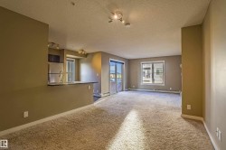 Empty room with carpet, a textured ceiling, track lighting, and a baseboard radiator - 