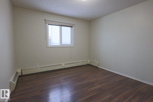 Spare room with dark wood-type flooring, a textured ceiling, and baseboard heating - 213 5065 31 Avenue, Edmonton, AB - Indoor Photo Showing Other Room