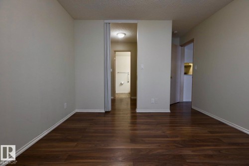 Unfurnished bedroom with a textured ceiling, dark wood-style flooring, and ensuite bath - 213 5065 31 Avenue, Edmonton, AB - Indoor Photo Showing Other Room