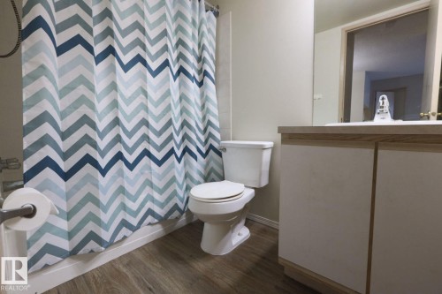 Bathroom with a shower with shower curtain, dark wood finished floors, and vanity - 213 5065 31 Avenue, Edmonton, AB - Indoor Photo Showing Bathroom