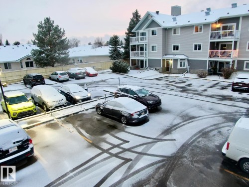 Parking at dusk with uncovered parking - 213 5065 31 Avenue, Edmonton, AB - Outdoor With Balcony