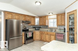 Kitchen with stainless steel appliances, brown cabinets, vaulted ceiling, backsplash, and light countertops - 