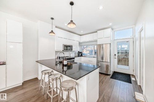 Kitchen featuring white cabinets, appliances with stainless steel finishes, modern cabinets, pendant lighting, and light wood-style flooring - 14812 98 Avenue, Edmonton, AB - Indoor Photo Showing Kitchen With Stainless Steel Kitchen With Upgraded Kitchen