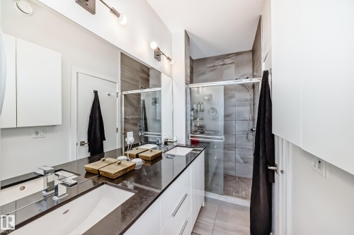 Full bathroom with double vanity, a stall shower, and light tile patterned floors - 14812 98 Avenue, Edmonton, AB - Indoor