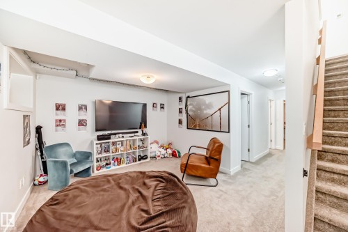 Living room featuring light carpet and stairs - 14812 98 Avenue, Edmonton, AB - Indoor Photo Showing Other Room