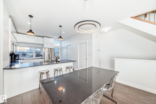 Kitchen with white cabinets, a kitchen bar, light wood finished floors, modern cabinets, and recessed lighting - 14812 98 Avenue, Edmonton, AB - Indoor Photo Showing Kitchen With Upgraded Kitchen