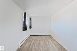 Unfurnished room with baseboard heating, a textured ceiling, and light wood-style floors - 