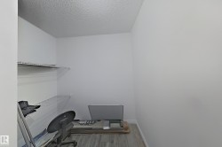 Home office with light wood-type flooring and a textured ceiling - 