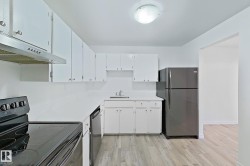 Kitchen featuring appliances with stainless steel finishes, light wood-style flooring, white cabinets, and under cabinet range hood - 