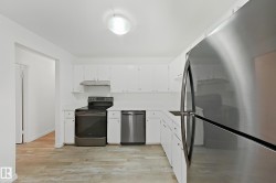 Kitchen featuring stainless steel appliances, light countertops, light wood-type flooring, and white cabinetry - 