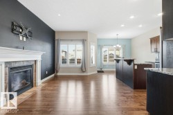 Living room featuring dark wood-style floors, a tiled fireplace, recessed lighting, and a chandelier - 