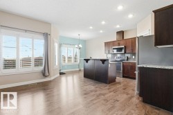 Kitchen featuring a breakfast bar, stainless steel appliances, a textured ceiling, light stone counters, and tasteful backsplash - 