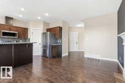 Kitchen featuring backsplash, stainless steel appliances, a kitchen breakfast bar, light stone counters, and a textured ceiling - 
