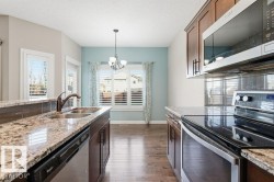 Kitchen with appliances with stainless steel finishes, a chandelier, dark wood finished floors, a textured ceiling, and healthy amount of natural light - 