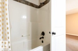 Bathroom with carpet floors, shower / bath combination with curtain, and a textured ceiling - 