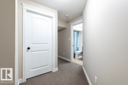 Hall featuring a textured ceiling and carpet flooring - 