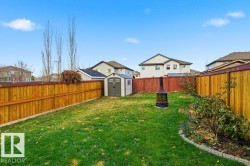 Fenced backyard featuring a shed, an outdoor fire pit, and a residential view - 