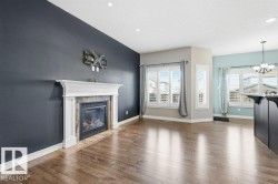Unfurnished living room featuring healthy amount of natural light, wood-type flooring, a tile fireplace, a chandelier, and recessed lighting - 