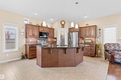 Kitchen featuring tasteful backsplash, a kitchen bar, dark stone counters, healthy amount of natural light, and lofted ceiling - 