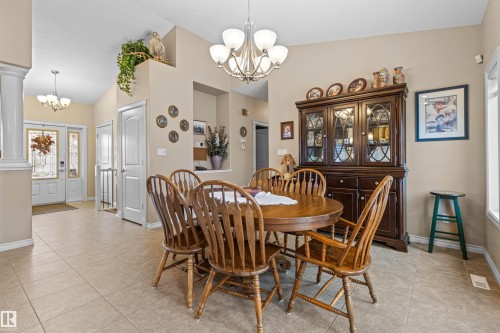 Dining room with a chandelier, light tile patterned floors, and high vaulted ceiling - 50 Willow Wood Lane, Stony Plain, AB - Indoor Photo Showing Dining Room